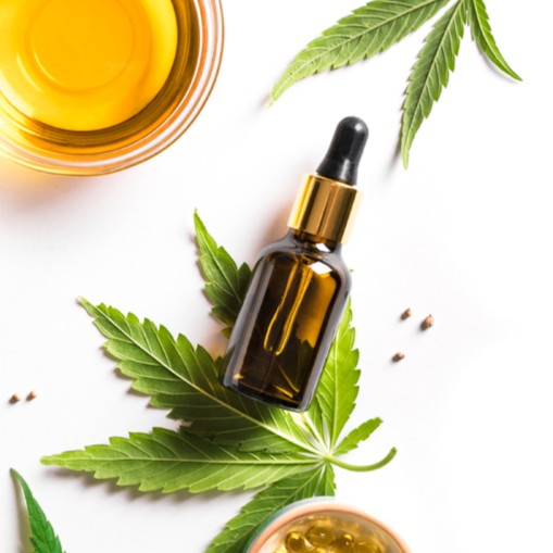 Picture of a Bottle of CBD Oil on Top of a Hemp Leaf with a Bowl of CBD Oil in Top Left Corner of Frame